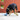 Dog playing with Kong Rewards Tipsy Treat Dispenser toy a blue toy on a concrete surface against a red brick wall.